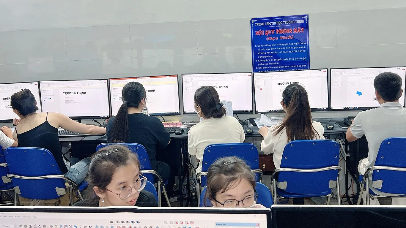 Học viên đang thao tác thiết kế slide trên máy tính dưới sự hỗ trợ của giáo viên